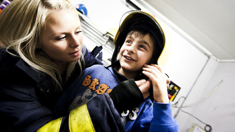 En ung student hjelper en gutt med å få på hjelmen.