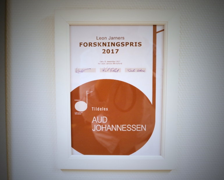Diplom for mottakelse av Leon Jarners Forskningspris innrammet og opphengt på Aud Johannessens kontor.