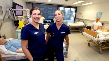 Sykepleierstudentene Sunniva Landsverk og Synne Poortman i et simuleringsrom med sykehussenger ved campus Drammen. 