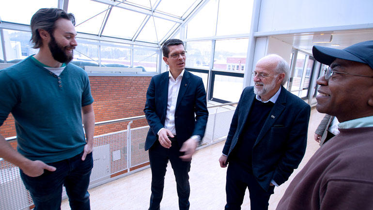 Konsernsjef Geir Håøy fra Kongsberg Gruppen og USN-rektor Petter Aasen i dress i samtale med to USN-studenter på campus Porsgrunn