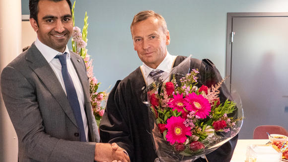 Ajmal Hafeez mottar blomster og gratulasjon fra dekan Hans Anton Stubberud ved USN Handelshøyskolen.