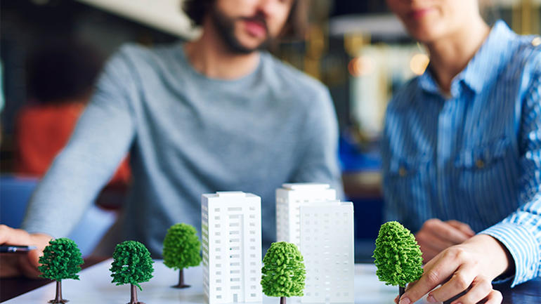 Personer med modeller av bygninger og trær. Foto iStock/gpointstudio