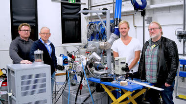 André Vagner Gaathaug, Dag Bjerketvedt, Joachim Lundberg og Knut Vågsæther står oppstilt foran teknisk system i lab.