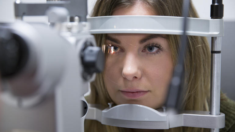 nærbilde av en kvinne som ser inn i et optikerinstrumentet
