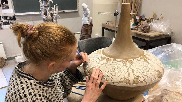 Student arbeider med vase av leire