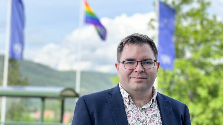 Portrett av førsteamanuensis Karl Christian Alvestad med regnbueflagget i bakgrunn.