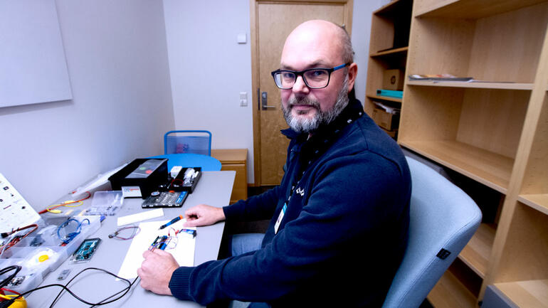 Lars-Cyril Blystad sittende på kontoret foran PC.