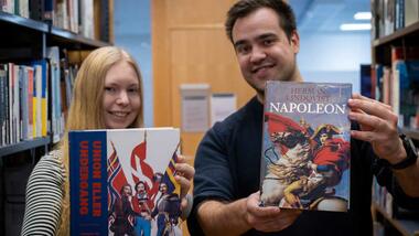 Bilde av to historiestudenter med bøker i bibliotek