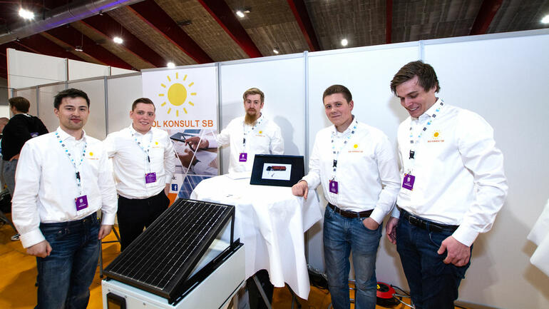 De fem ingeniørstudentene i hvite like skjortet på stand under regonmesterskapet for studentbedrifter viser frem solcellepanel  testplater