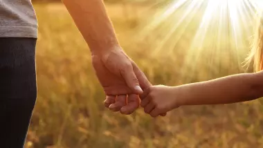 Nærbilde av hendene til barn og voksen som holder hverandre