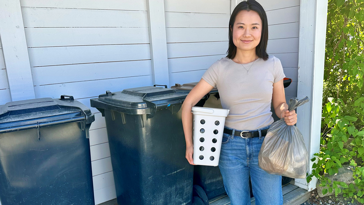 Bilde av stipendiat Lucy Zhou Korvald ved avfalssbeholdere