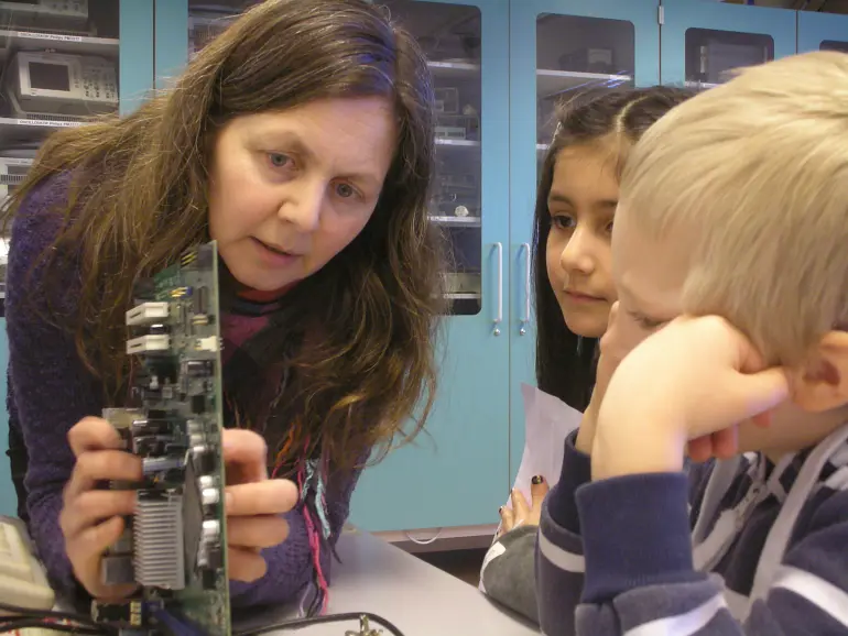 kvinne bak mikroskop sammen med to barn