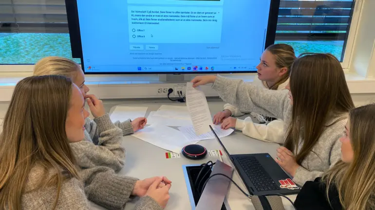 elever har gruppearbeid ved bord med ark og pc