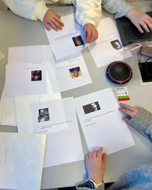 papir med oppgaver på et bord med hender