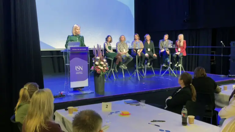 statsråd sigrun aasland taler fra usn-talerstol på konferansescenen der det sitter flere og hører på