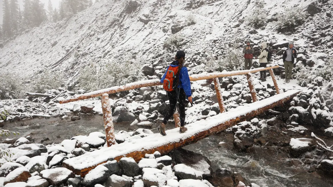 Personer som går over en liten bro dekt av snø