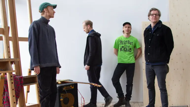 fire menn og en gitar på en forsterker