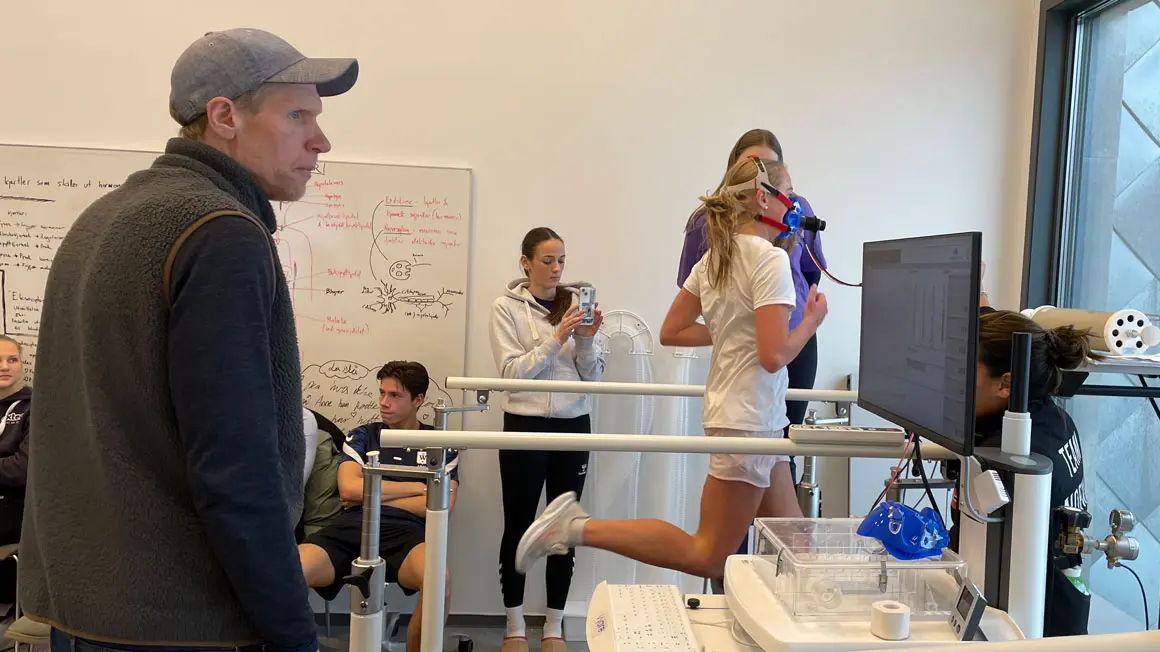 jente løper på tredemølle med maske, måles på datamaskin