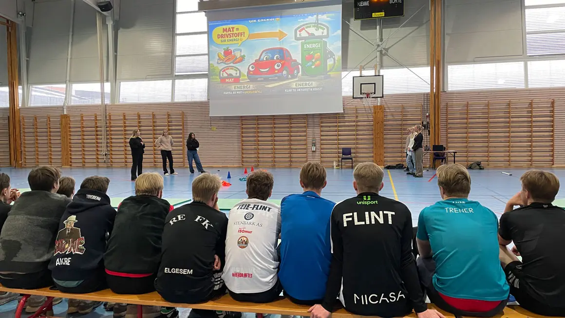 rygger i gymsal foran storskjem med info om ernæring