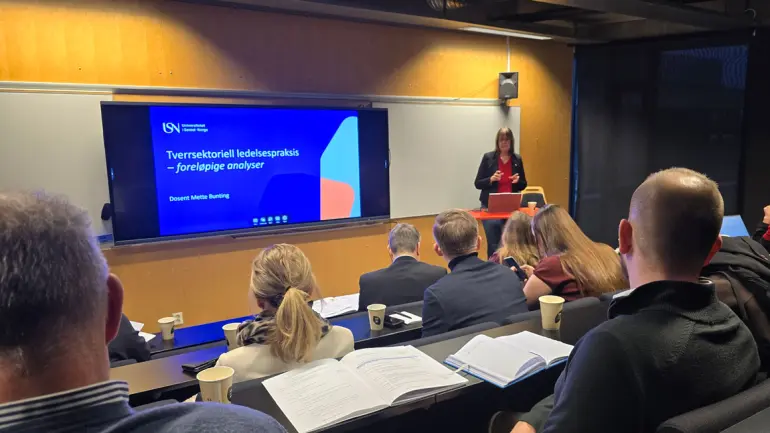 bilde av auditorium med folk som følger presentasjon fra USN