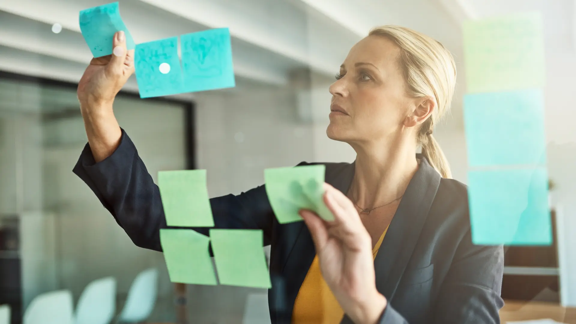 bilde av kvinnelig leder ved tavle med post-it-lapper