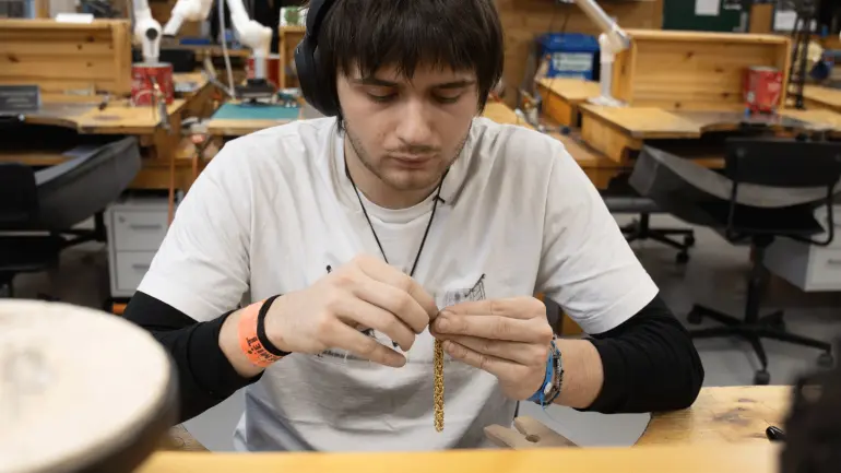 student Gustav Vermot lager eit smykke på metallverkstaden. Foto