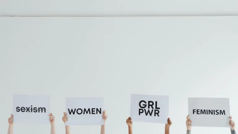 hands in the air holding posters saying: GRL POWR, Feminism and WOMEN. photo