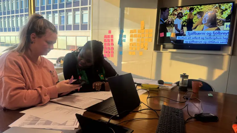 to studenter sitter ved en bord med mange ark og tastatur