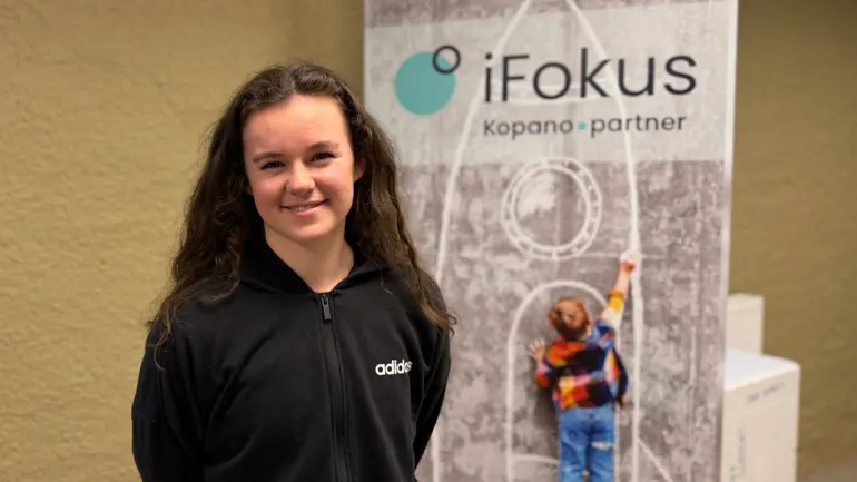 smilende ung dame foran plakat for iFokus