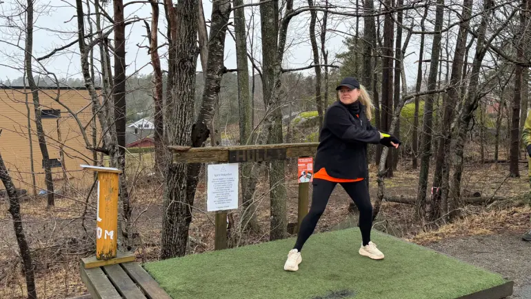 Dame i treningstøy kaster frisbee