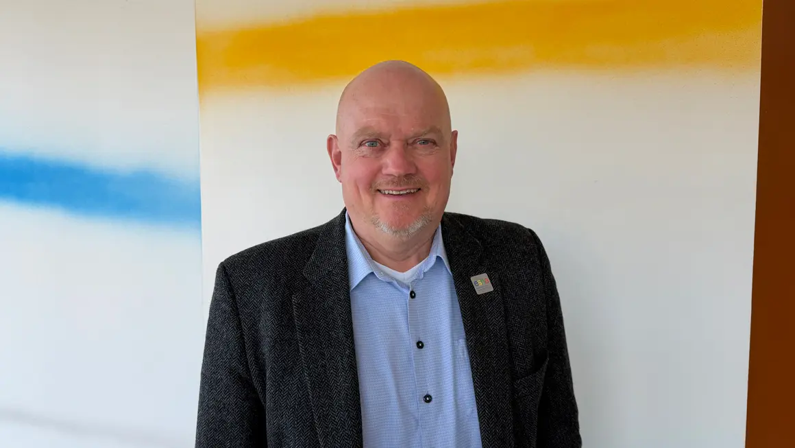 Portrett av mann i dressjakke som smiler 