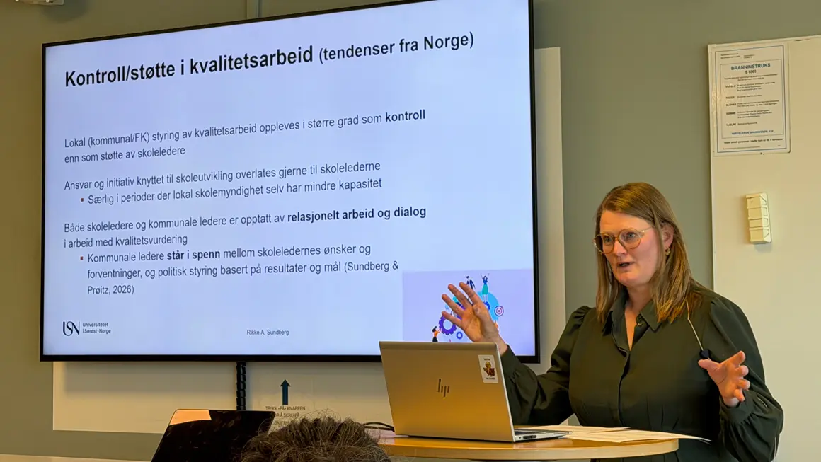 dame i grønn kjole presenterer foran skjerm