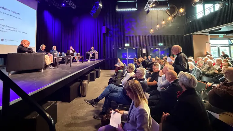 sal full av folk og panel på scene