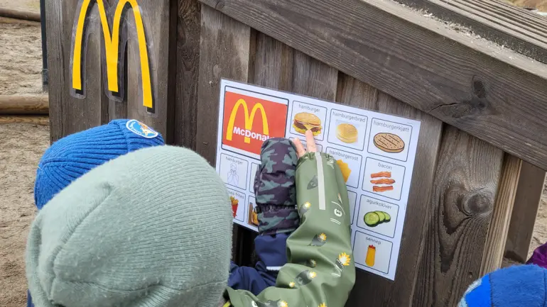 barn som bruker ASK symboler til å bestille i en leke-McDonalds i barnehagen