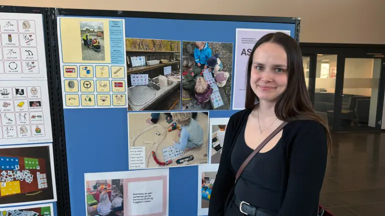 Student står foran presentasjon av ASK-tavler i barnehagen