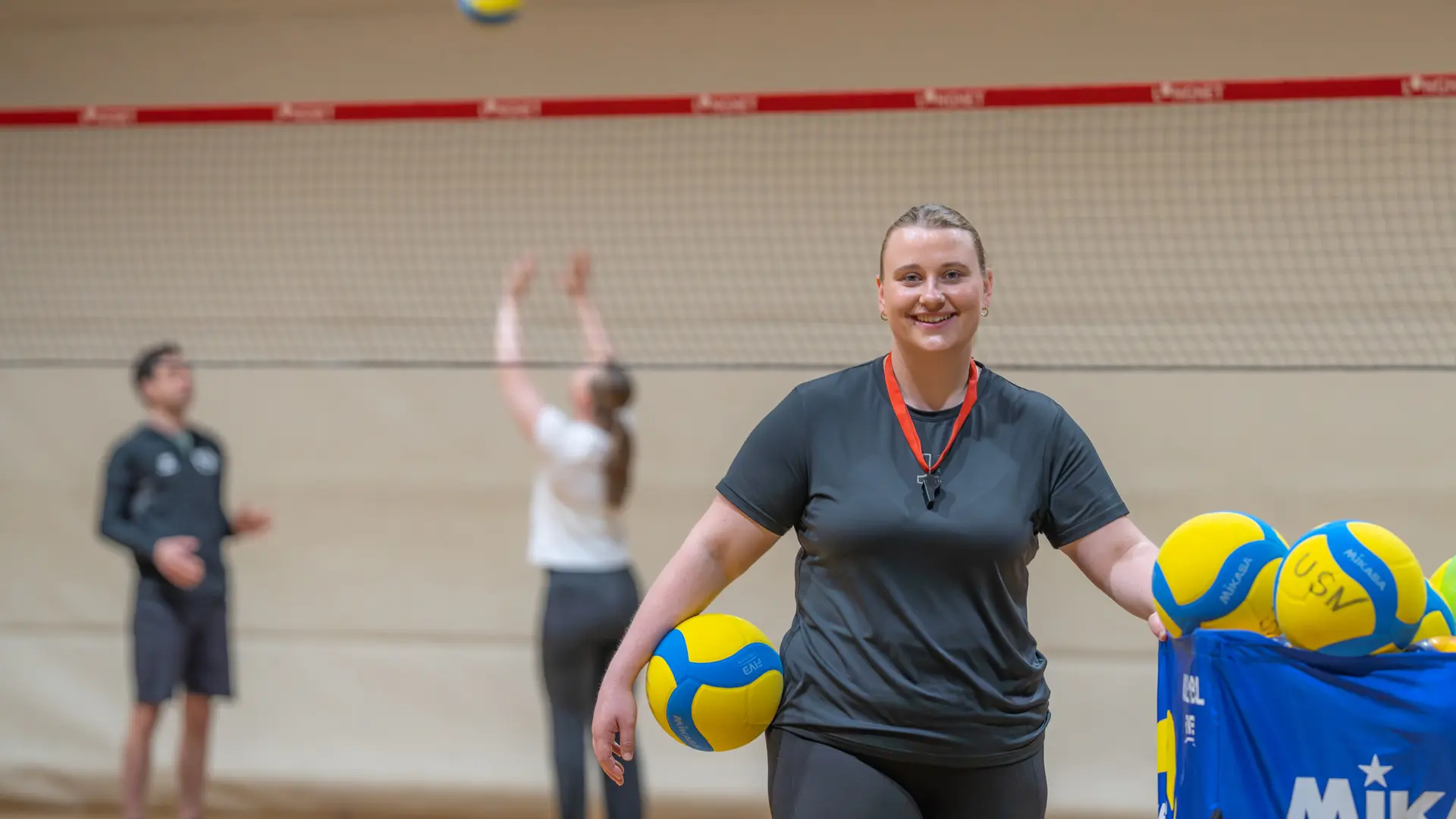 volleyballtrener på banen med kurv full av baller