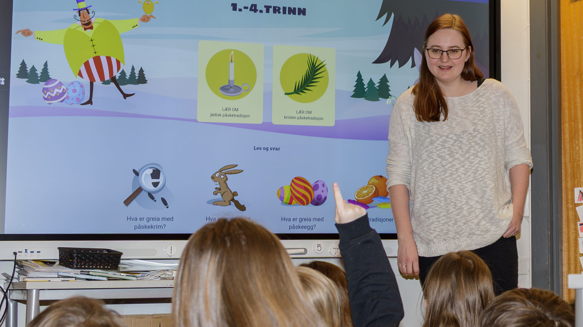 lærer i klasserom med elever som rekker opp hånda