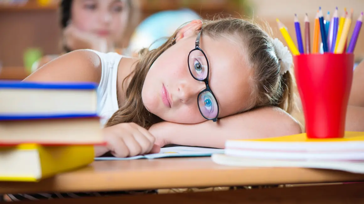 jente ved skolepulten som kjeder seg