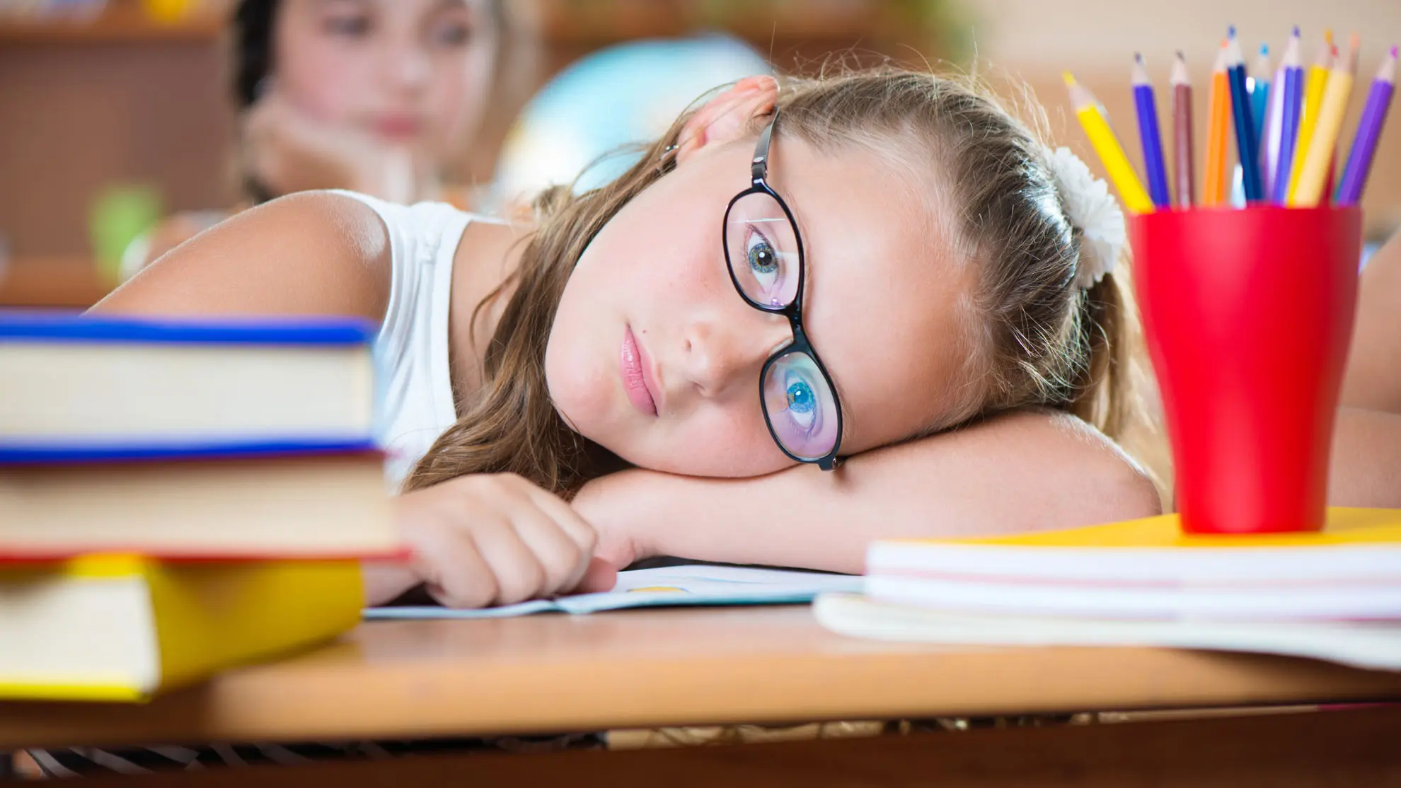 jente ved skolepulten som kjeder seg