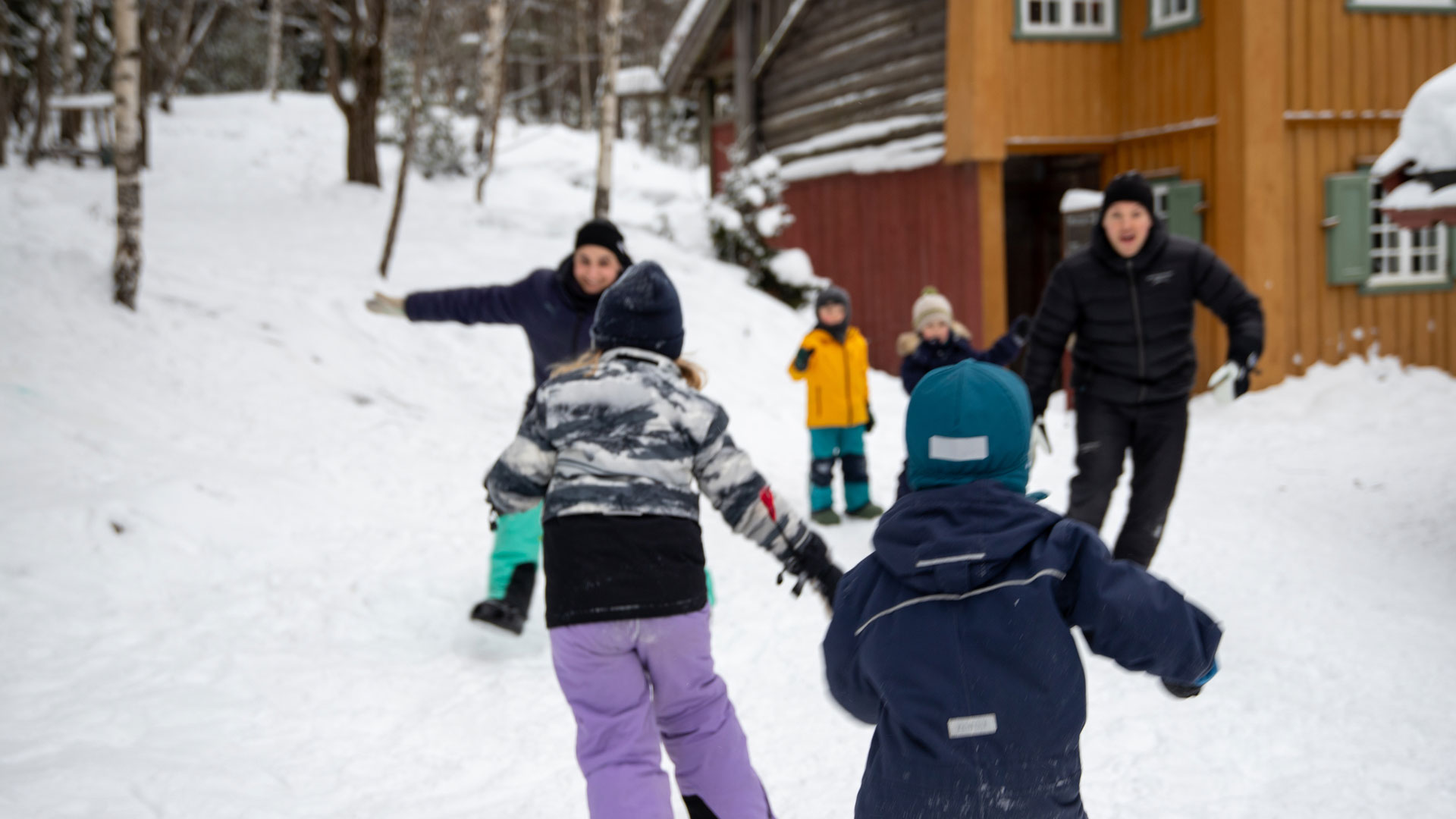 Barn som løper mot en voksen i lek ute i snøen