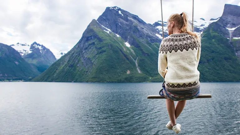 Woman with Nordic features on a swing in front of a spectacular fjord view. photo