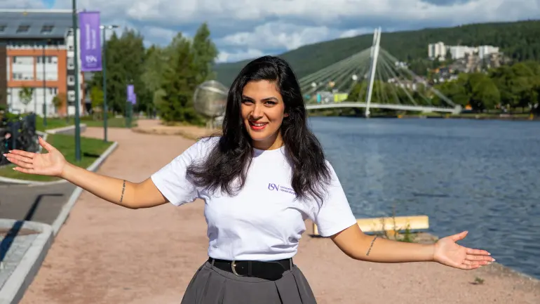 Kvinnelig student, smiler til kamera med åpne armer i Drammen.