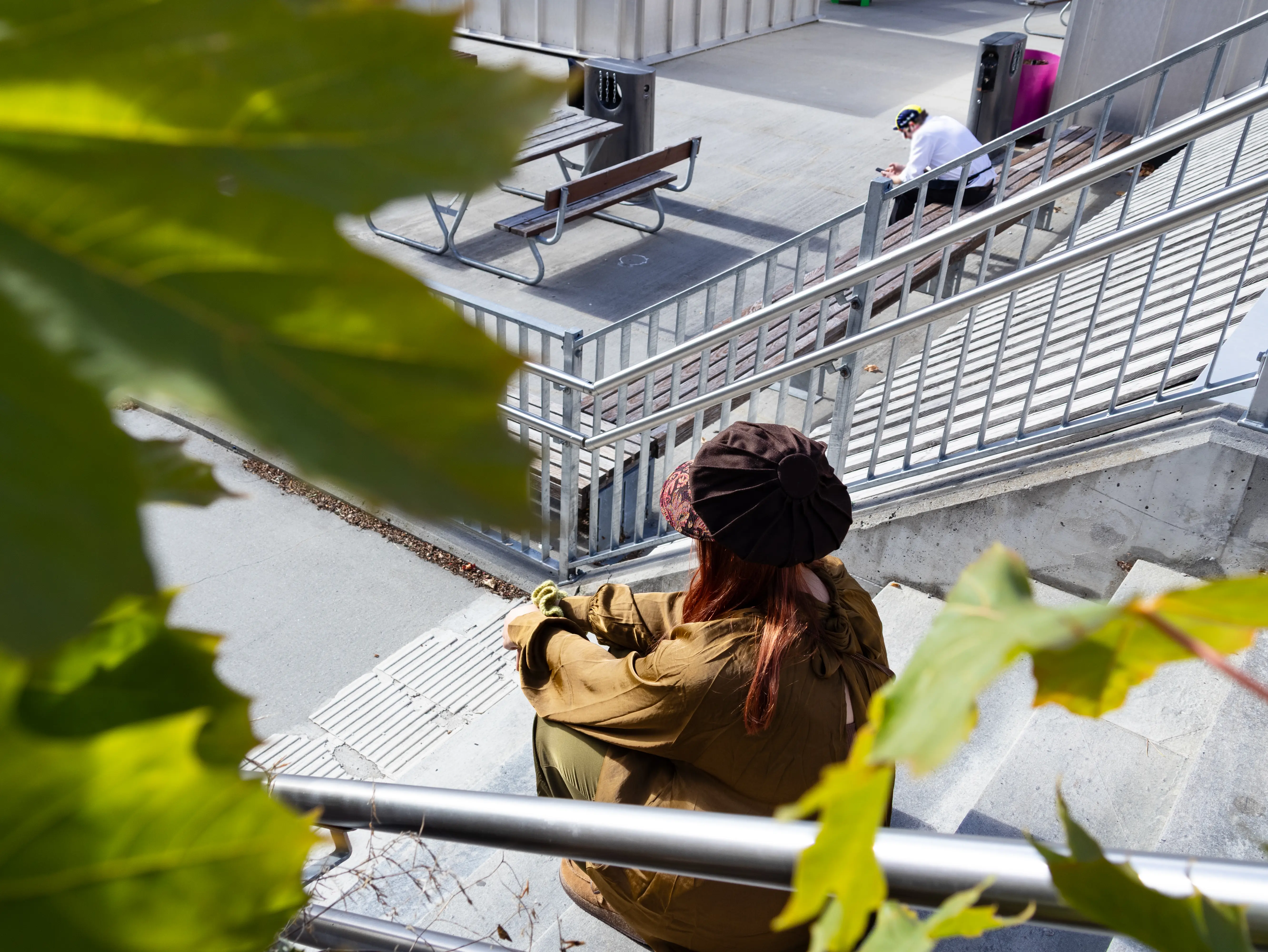 Marie sittende i trappen  utendørs, busker i forgrunnen,, og hun har ryggen til som illustrasjon på utenforksap