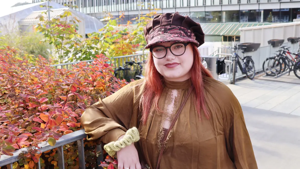 HJELPER FORSKERE: – Jeg føler at forskerne lytter til det jeg har å si. Det har gitt meg mer selvtillit, sier Marie Lien Halvorsen om rollen som medforsker. (Foto: An-Magritt Larsen) Portrett av Marie i halvfigur, stående ute og støtte seg til et gjerde med armen oppå, høstbusker i bakgrunnen ig ikledd høstfarger med hatt med skjerm.