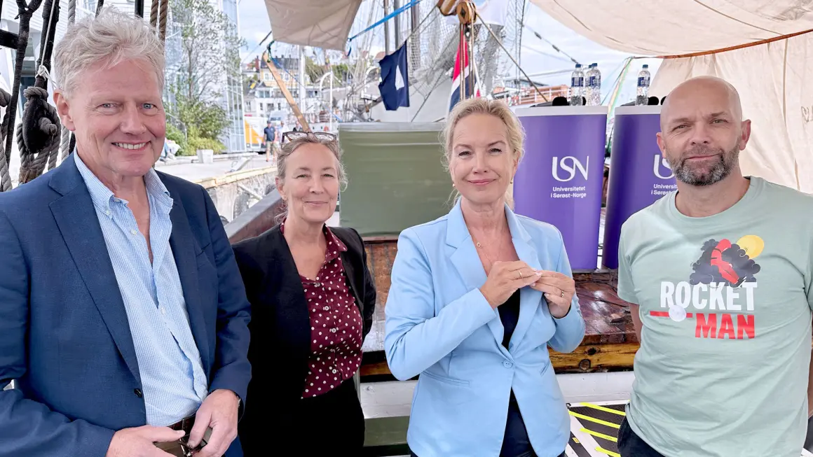 TETT PÅ ARBEIDSLIVET: Forskningsprosjektet på ungt utenforskap finansieres av lokale sparebankstiftelser. Fra venstre Bjørn Engaas i Sparebankstiftelsen Nøtterøy-Tønsberg, forsker Kjersti Røsvik, prosjektleder Vibeke Krane og daglig leder Thomas Fjeldstad i Rocket-Man. (Foto: An-Magritt Larsen) Forskerne og represtant fra fiansirø og virksomhet som lykkes med inklidering av unge stående på rekke og smiler til kamera. Bildet er tatt om bord i ishavsskuta Berntine under Arendalsuka 2026.