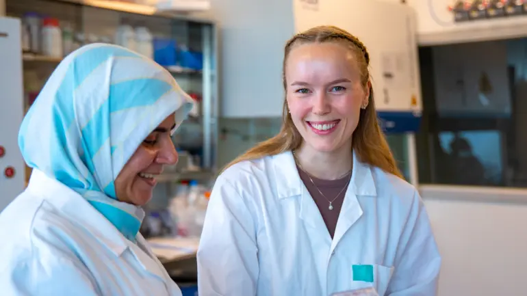 To kvinnelige forskere i hvit labfrakk i laboratorium som illostrasjonsbilde. 