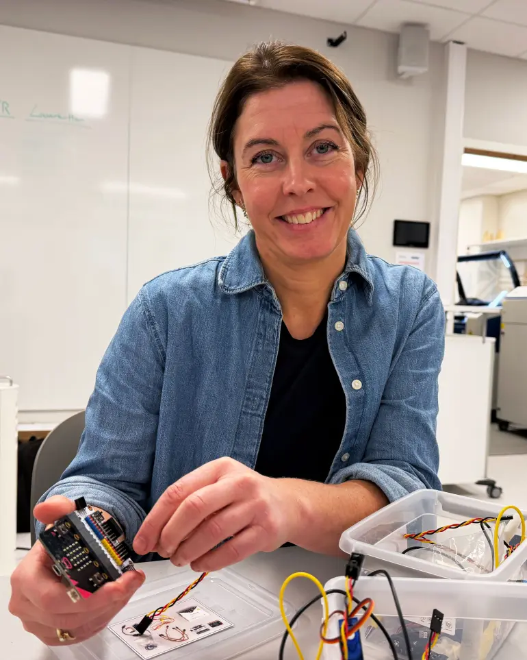 smilende dame med ledninger og programmeringsutstyr