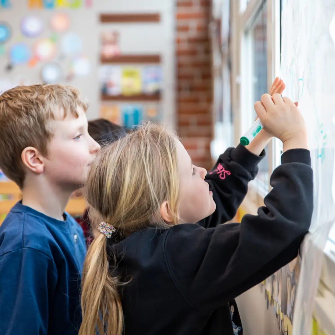 Elever skriver på et ark på et vindu i klasserommet
