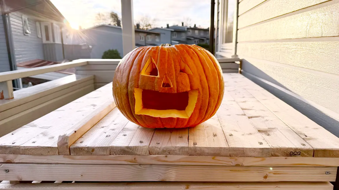 FRA PYNT TIL MAT: Når gresskarene er skåret ut til lykter for halloween, hva gjør du med innmaten? (Foto: Helene Ekeberg Schmidt) Et oransje gresskar skåret ut sil skummelt ansikt og brukes som lykt til halloween. Gresskaret er fotografert på en tretrapp inntil en husvegg.