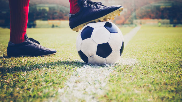 Bilde av fotballspillers føtter, støvler på ball. 